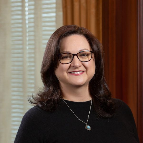 Debbie Bazarsky, the director at the LGBTQIA+ Center for Faculty and Staff, with her hair down to her shoulders, wearing a black shirt, a necklace, and glasses.