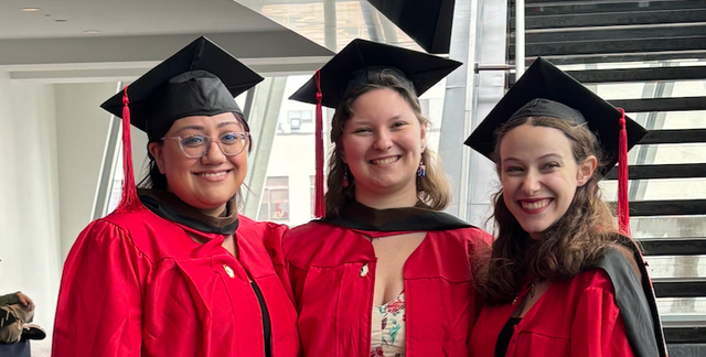 Three MFA students in graduate regalia smiling
