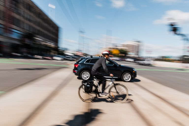 Cyclist on Commonwealth Ave with cars and train