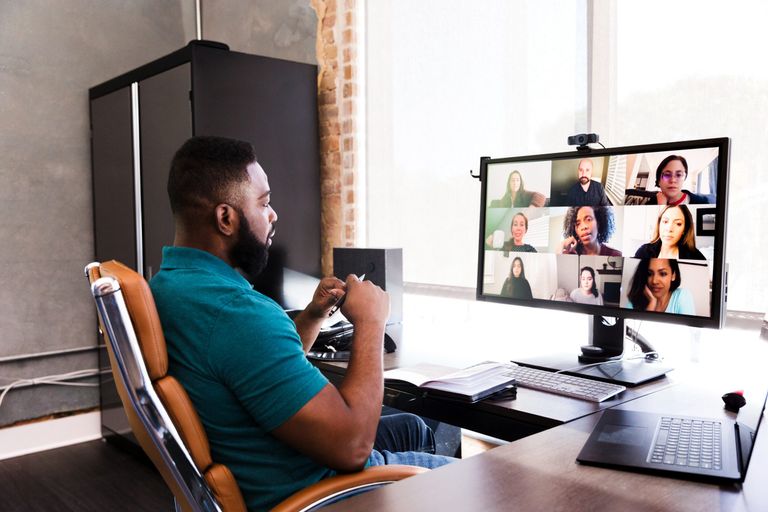 Man sitting in office chair in front of teleconferencing screen