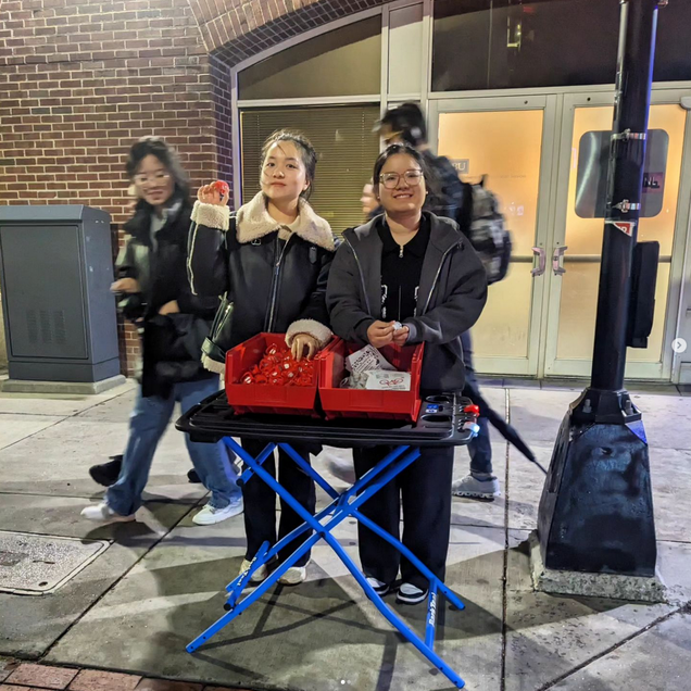 Smiling students distributing bike lights at night on Commonwealth Ave