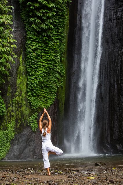 woman meditating doing yoga between waterfalls