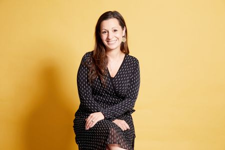 Amie Grills posed infront of a yellow background