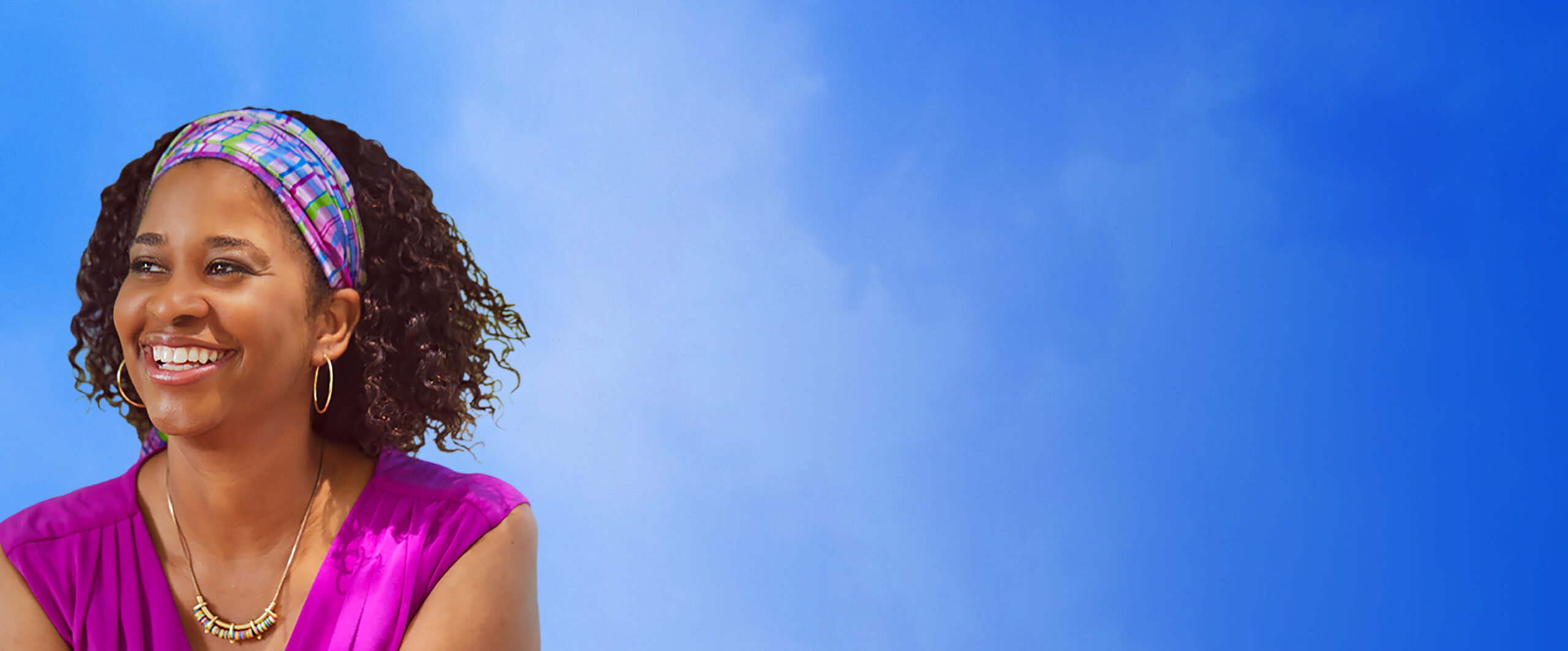 Women in bright pink shirt looking out with a blue sky background