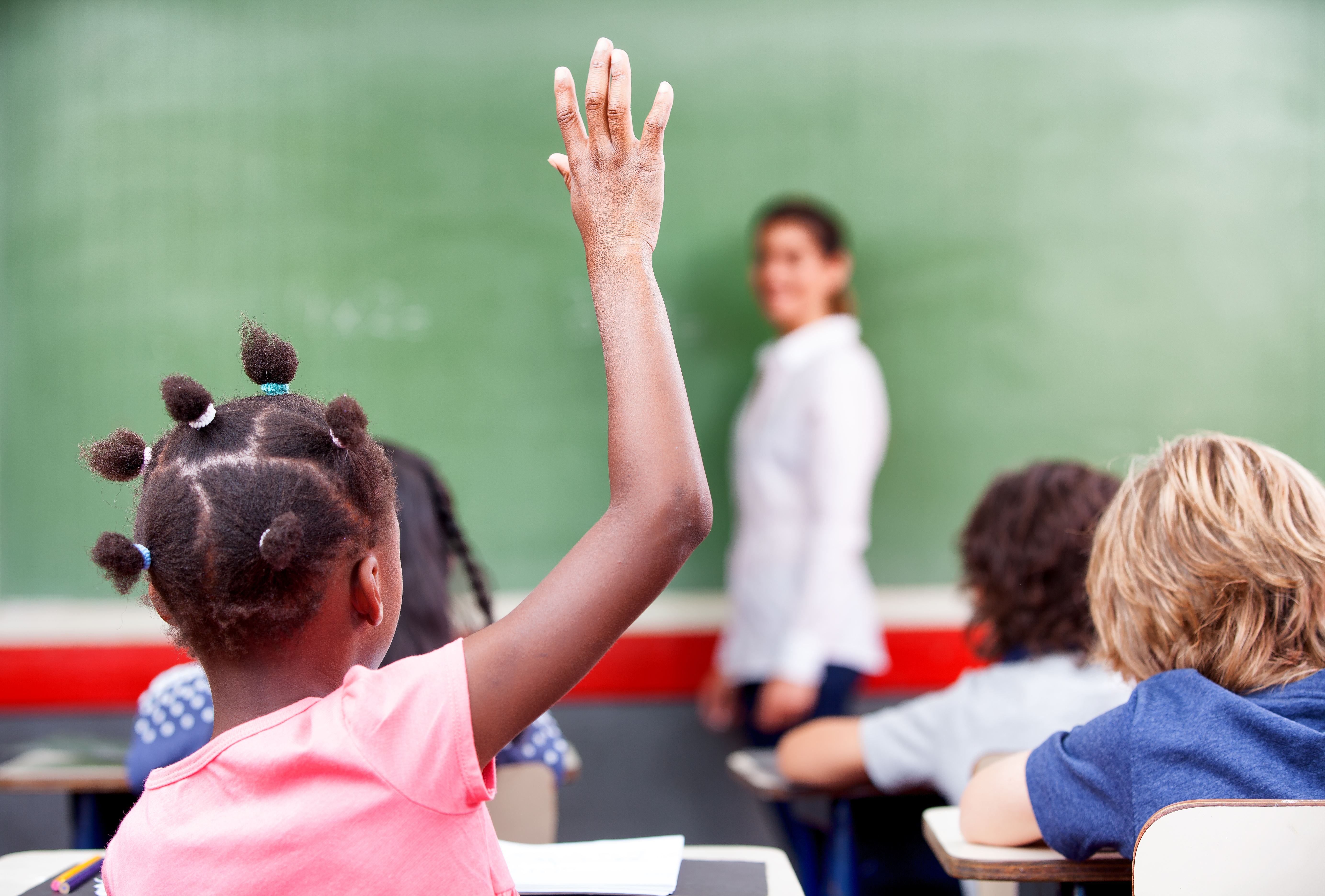 Young girl with hand raised in class