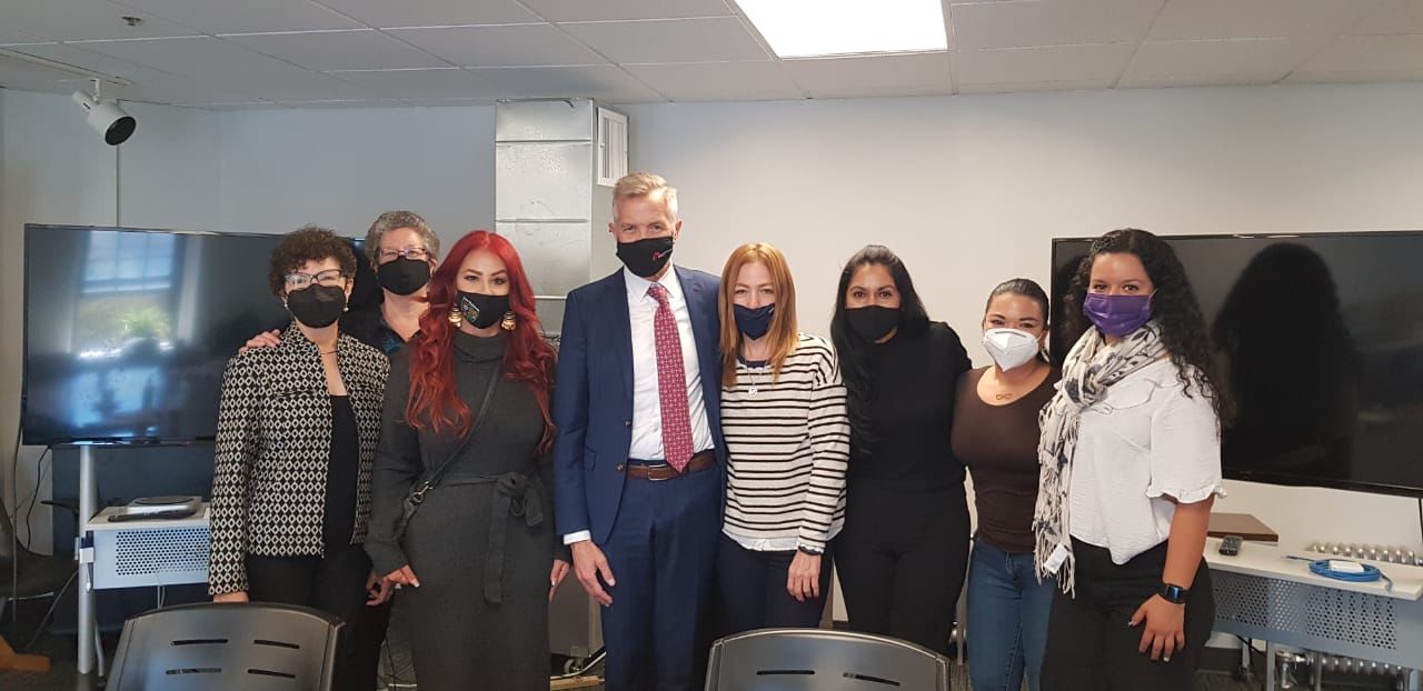 A group of people standing smiling in a classroom with masks on