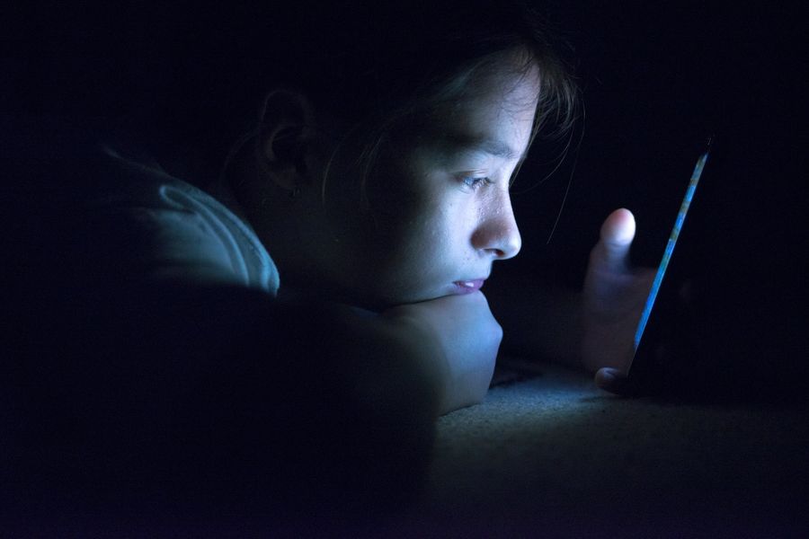 A child stares at his phone in a dimly lit room.