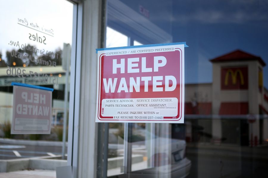 A "Help Wanted" sign is posted in the window of an automotive service shop
