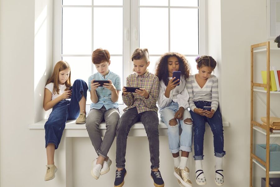 A group of children sitting together and checking their phones.