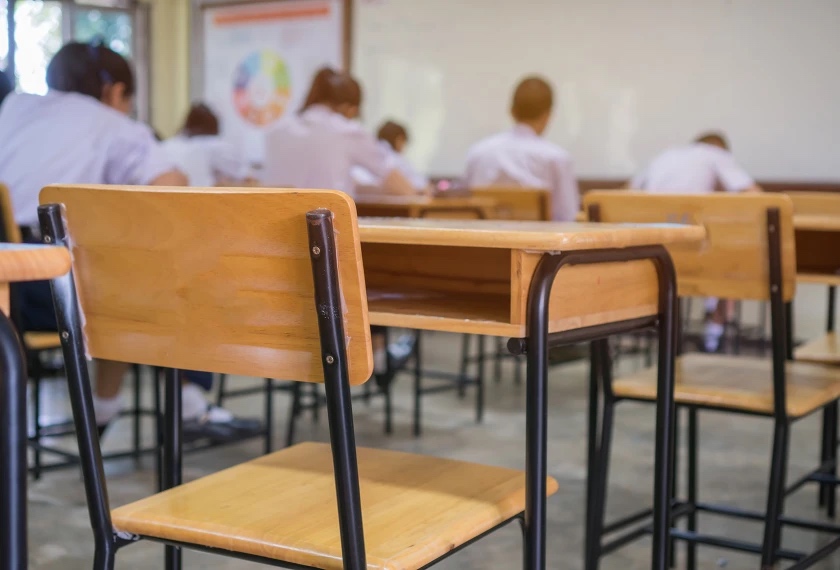 A photo of a classroom. There are a lot of empty desks in the room.