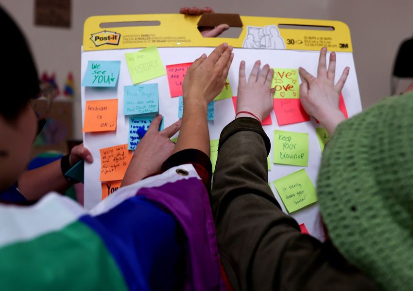 A group of children attacking Post-It notes to a flipboard on the wall.