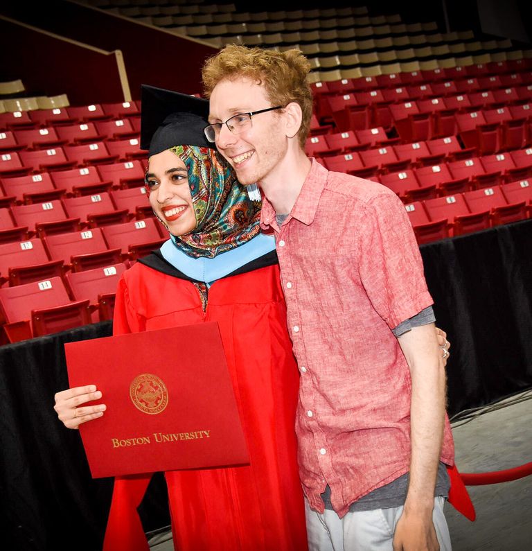 Graduating student with loved one smiling at commencement