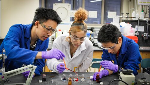 Shows three high schools students in a science lab