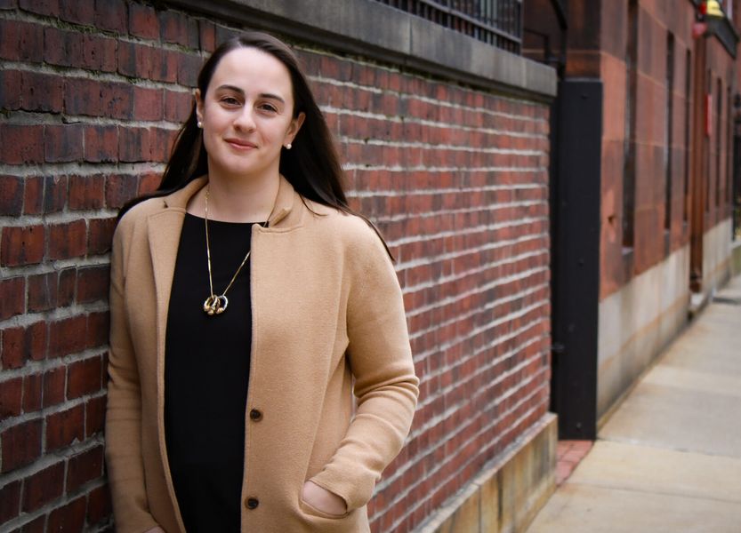 Kyle Cook Leaning against a brick wall on Boston sidewalk