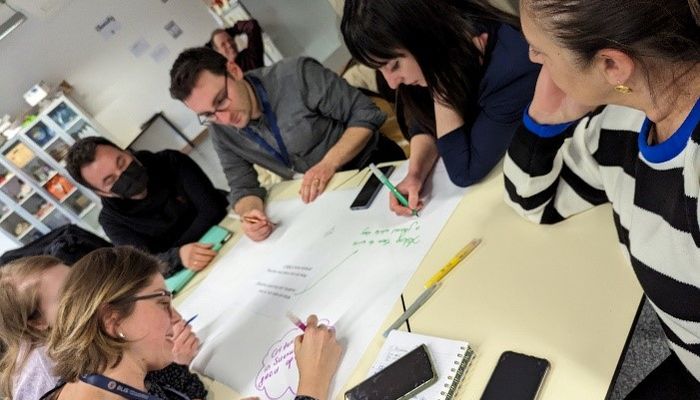 Shows five teachers working at a table