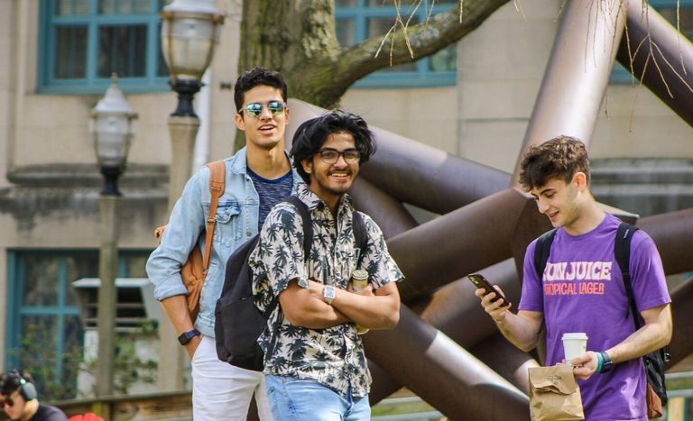 Three male students hanging on on BU beach on sunny day