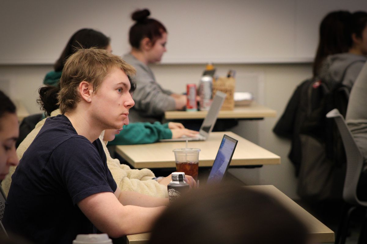 Blonde man listens to class surrounded by classmates