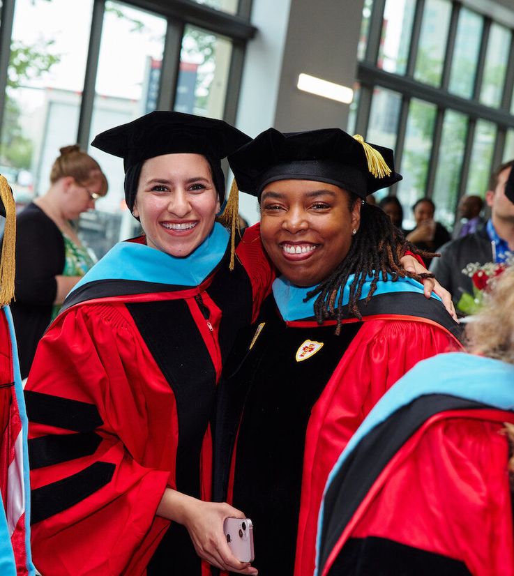 two students embracing after their doctoral hooding