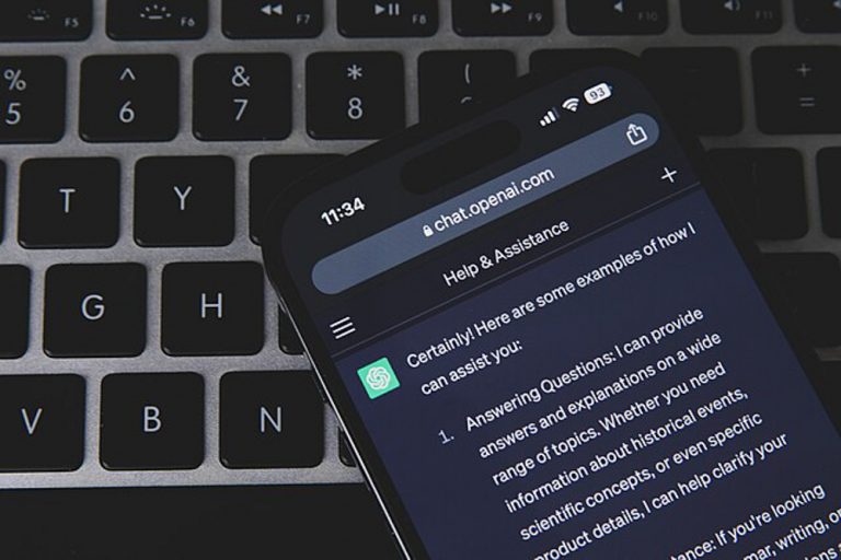 A photo of an iPhone with ChatGPT open. The phone is lying on top of a MacBook.