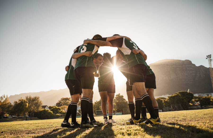 a soccor team in green uniforms huddle together during a game