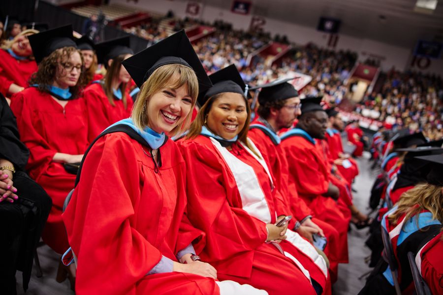 row of students smiling at the camera in full regalia