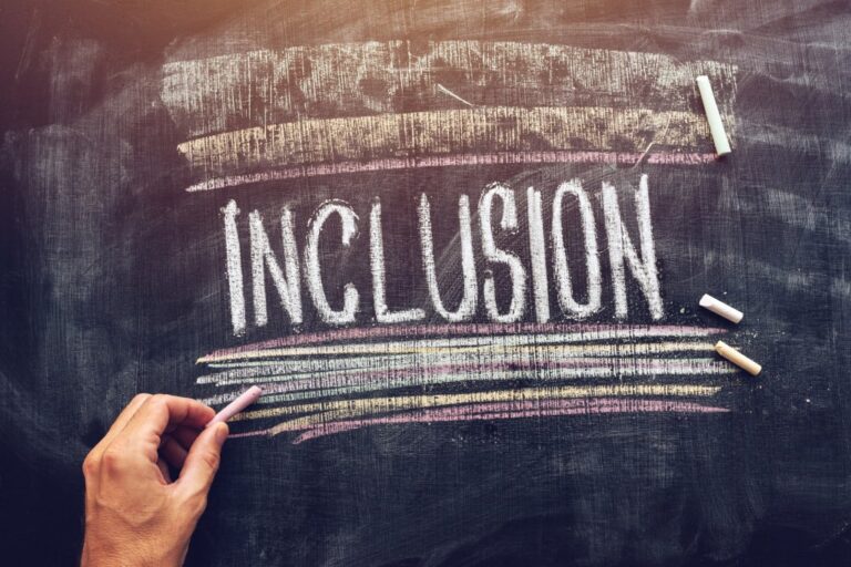 Someone writing "Inclusion" on a chalkboard