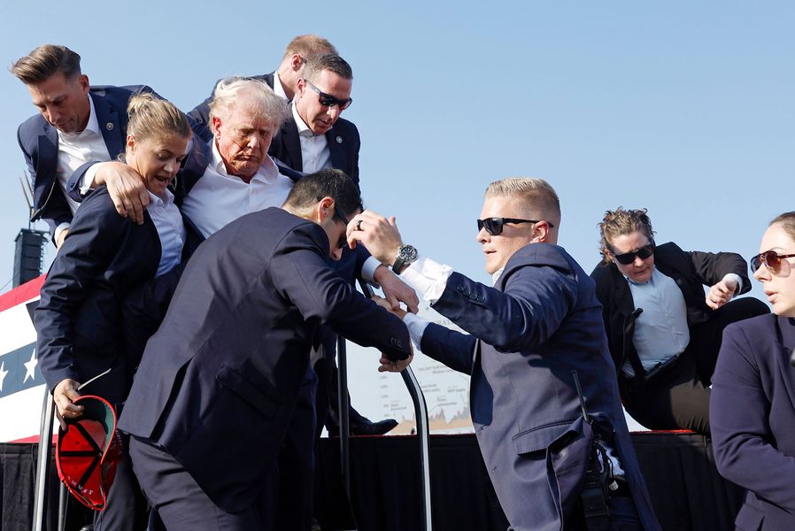 A wounded Donald Trump surrounded by Secret Service agents.