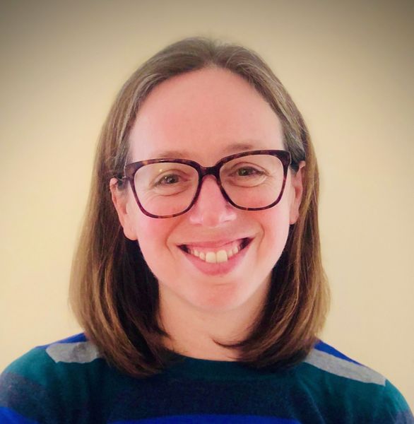 Shows Jennifer Lillis, who has shoulder length brown hair and is wearing glasses and a striped shirt