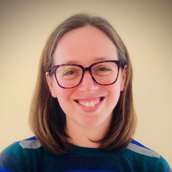 Shows Jennifer Lillis, who has shoulder length brown hair and is wearing glasses and a striped shirt