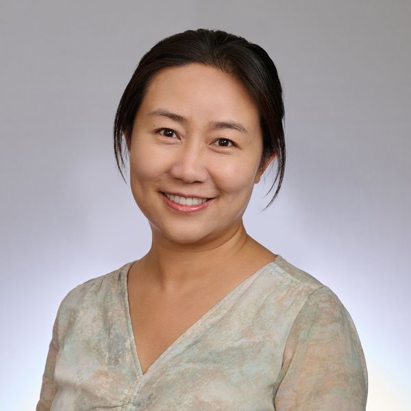 Shows Pei Wang, who has black hair she is wearing up and an off white v neck top