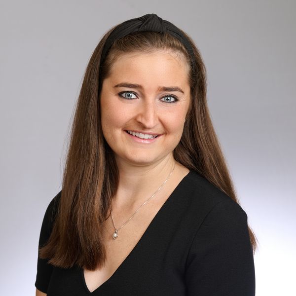 Shows Victoria Mulkern, who has long brown hair and is wearing a v neck black top