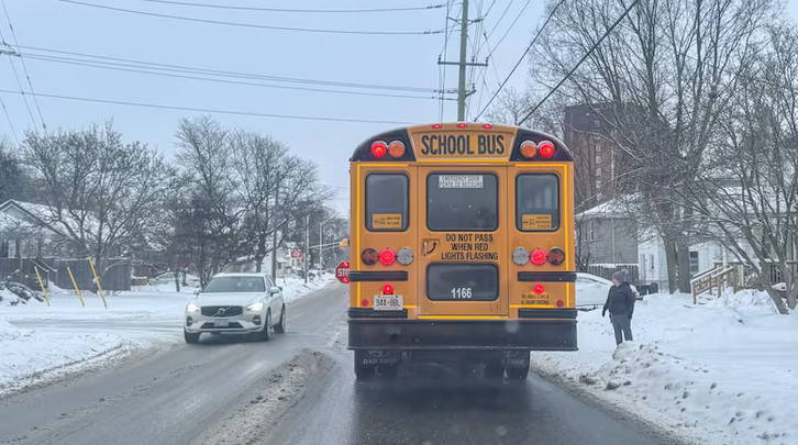 The back of a yellow school bus on a snowy street