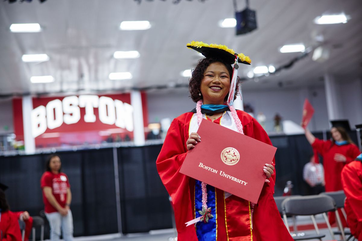 At Convocation, graduate student Julia Fernandez walks holding her BU Wheelock diploma