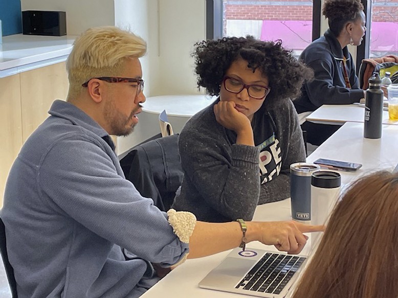 Two people doing work together at a computer