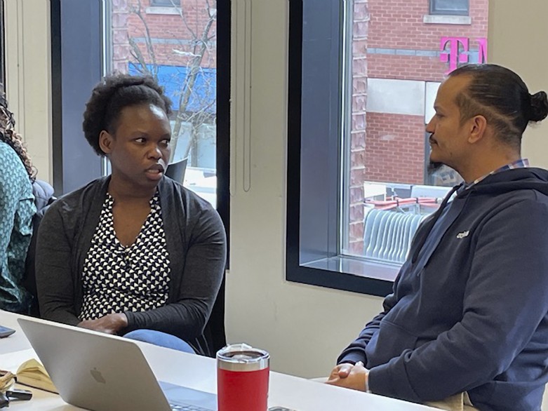 Two people talk in front of a computer