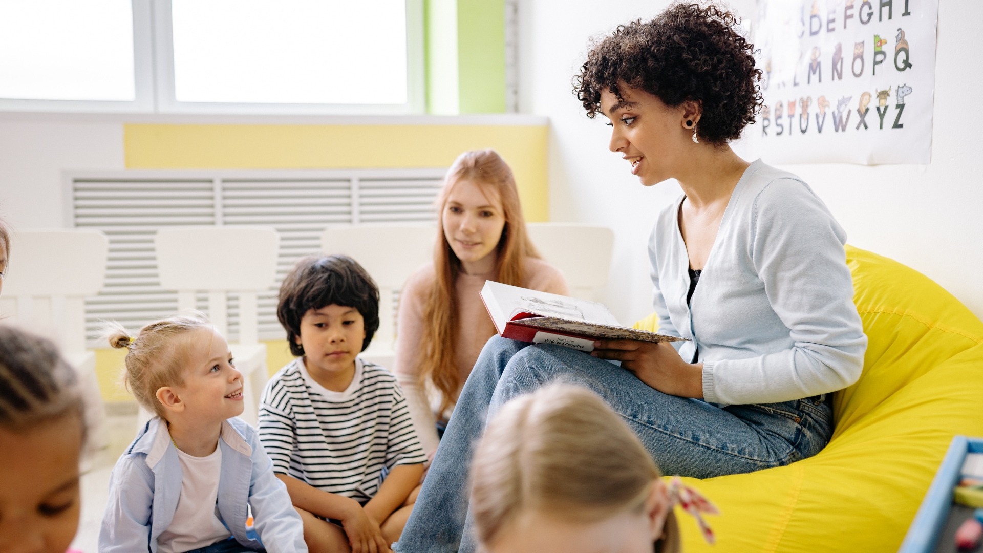 Female reading books to a group of children in school