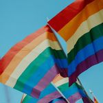 Pride Rainbow Flags against a blue sky background.