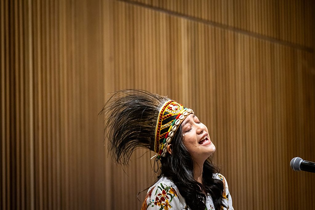 Sisilia Marpaung (CFA’25) sings a Biak song, followed by a Bahasa song of Indonesia while wearing a Papua crown during the Women of Color Circle's International Women's Day Celebration