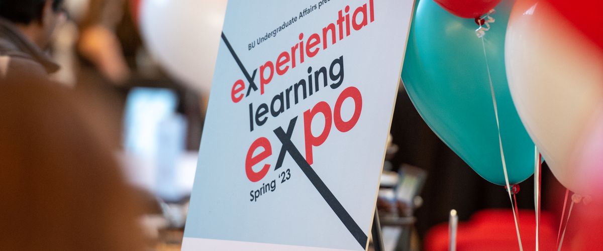 The official expo poster is displayed. Behind it, balloons can be seen.