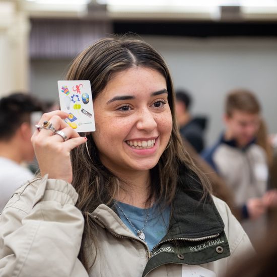 A female student is presenting a card with a smile.